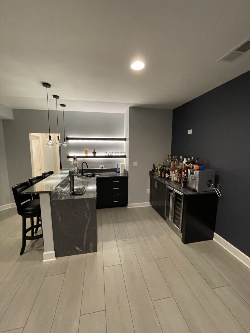 A kitchen with black and white cabinets, bar stools, and a counter.