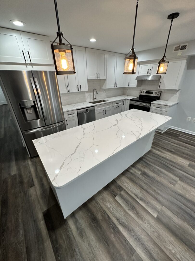A kitchen with white cabinets and marble countertops.
