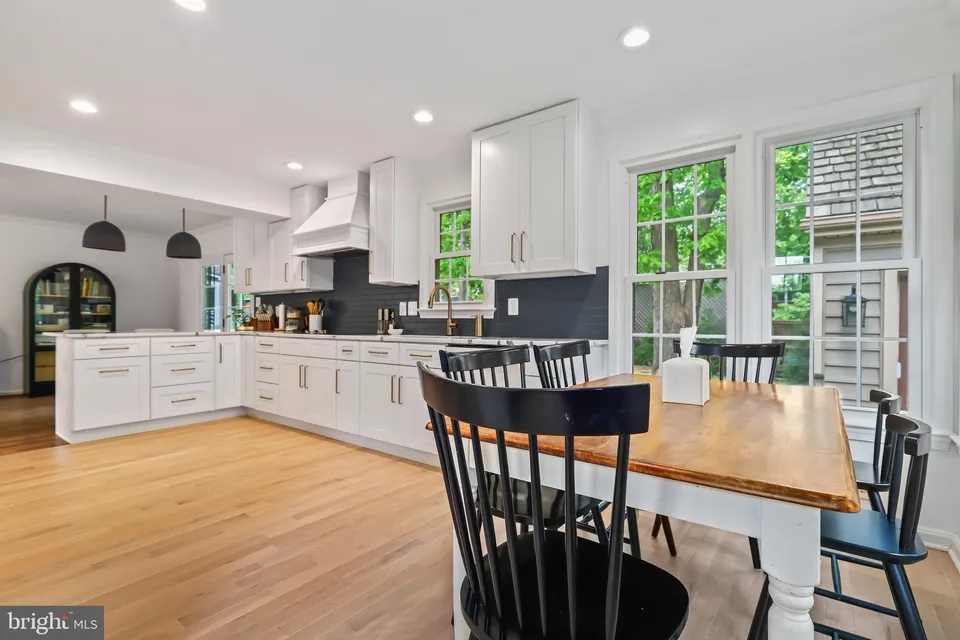 A kitchen with white cabinets and wooden floors.