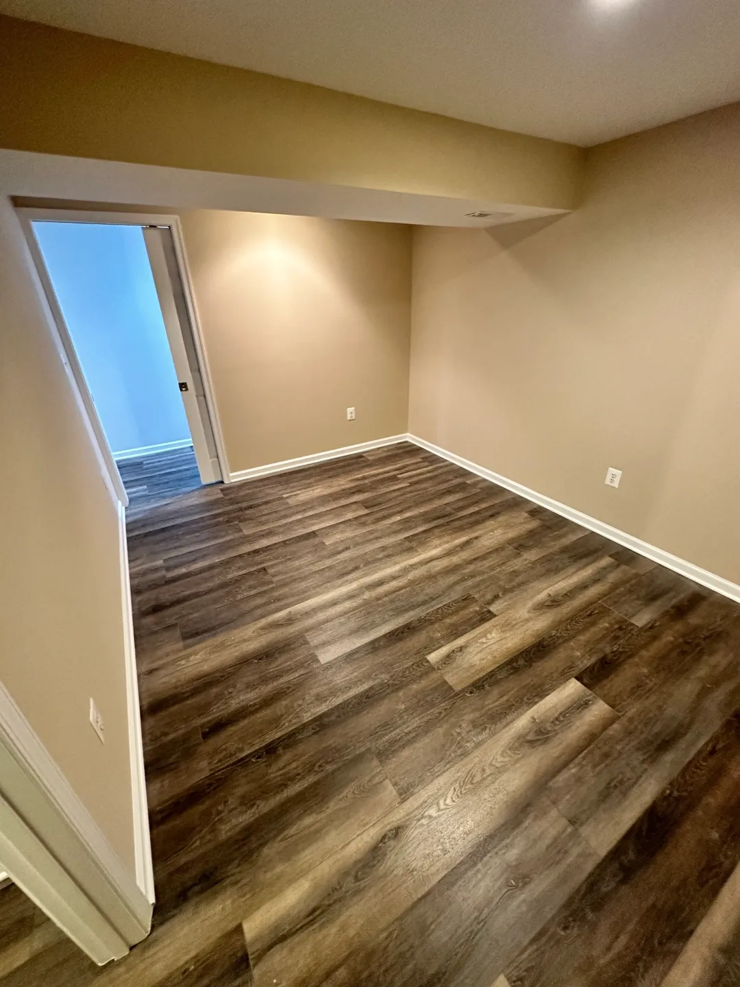 A room with wood floors and a door open.