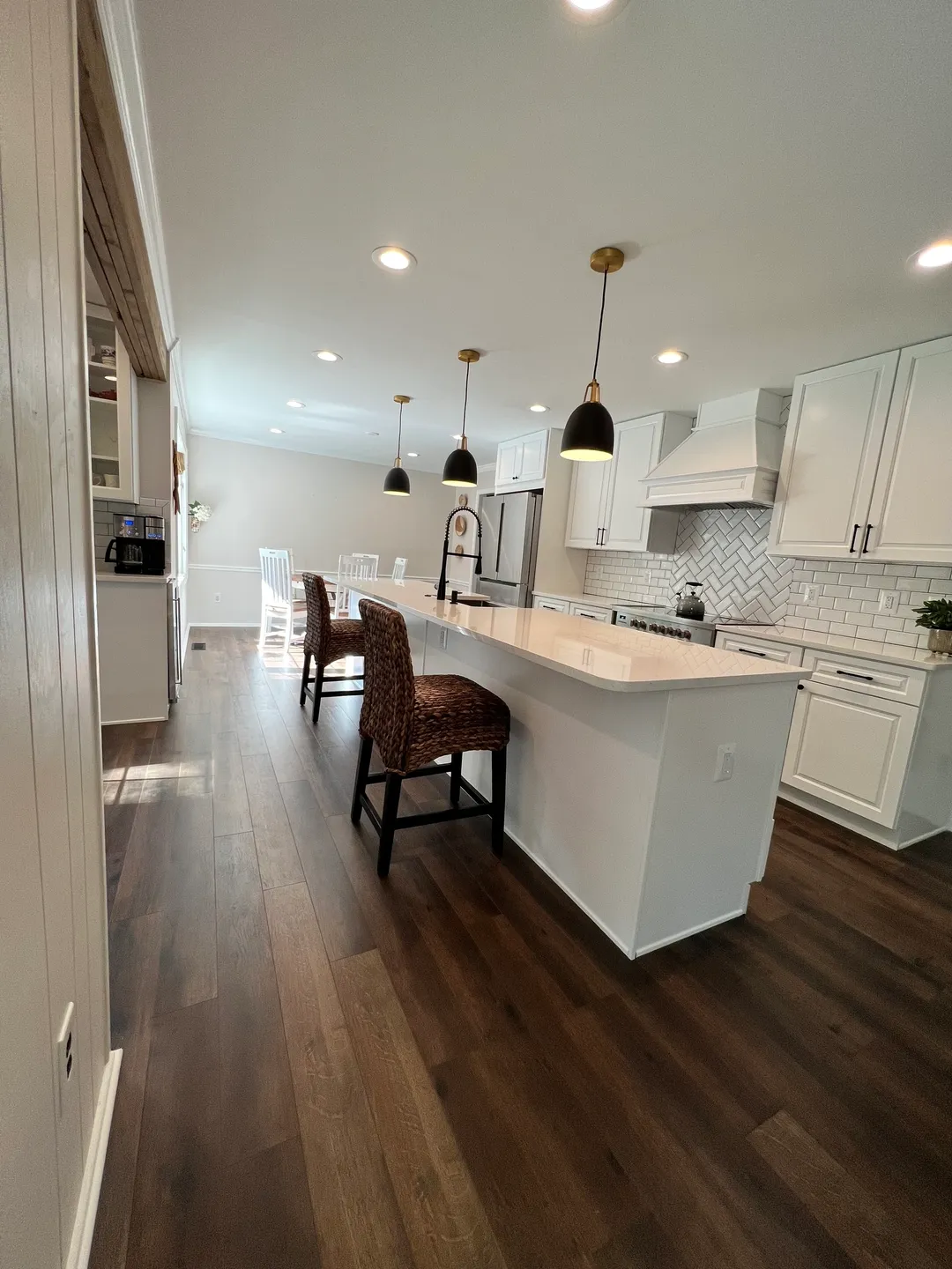 A kitchen with white cabinets and wood floors.