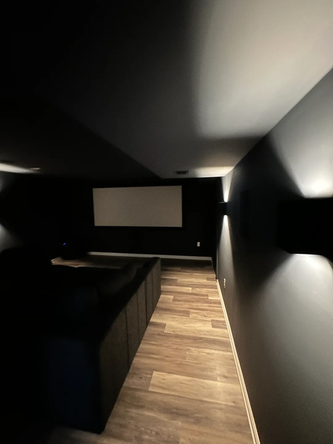 A room with a projector screen and a wooden floor